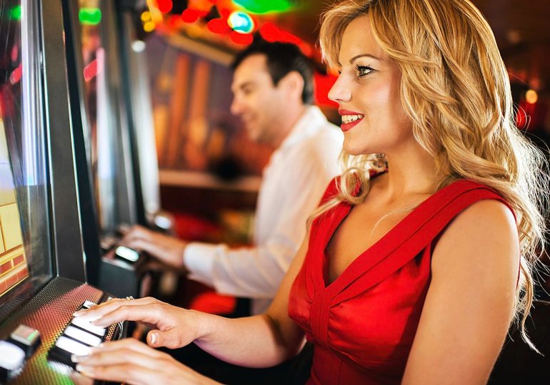 Женщина сидит за игровым автоматом в ожидании выигрыша